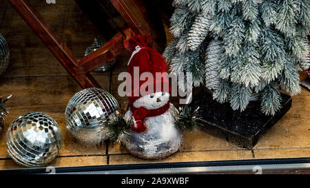Snowman toy in a hat under the Christmas tree. Stock Photo