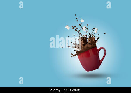 Cup of splashing hot chocolate with marshmallows as gift boxes shape on blue background. Christmas and New Year holidays concept. Copy space Stock Photo