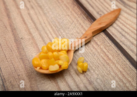 Sweet corn kernels on a wooden spoon on a wooden table. Fitness diet. Healthy diet. For a sweet treat. Close up Stock Photo