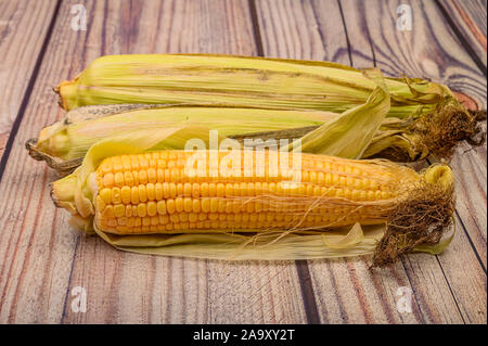 Three raw ears of corn on a wooden table. Healthy diet. Fitness diet. For a sweet treat. Close up Stock Photo