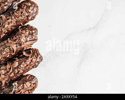 Set of homemade eclairs with chocolate on marble background. Close up view of delicious healthy profitroles with chocolate glaze. Copy space for text or design. Top view or flat lay. Stock Photo