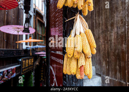Dry corncobs hanging on a wooden house in Xijiang Qianhu Miao Village (One Thousand Household Miao Village) , in Guizhou province of China. Stock Photo