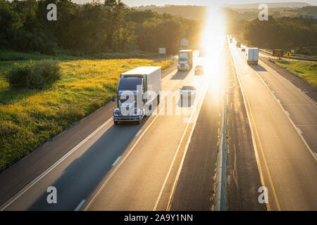 Semi Trucks 18 wheelers and cars on multiple lane highway Stock Photo