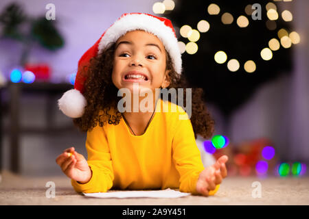 Emotional african american little girl writing letter to Santa Stock Photo