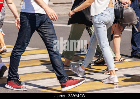 pedestrians crossing the road at a crosswalk in the city on summer day. legs closeup Stock Photo