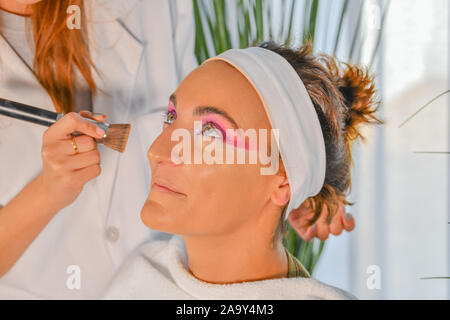 Professional makeup artist working with young woman Stock Photo