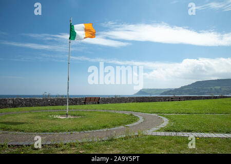 Irish flag flying in Carnlough, a village in County Antrim, Northern Ireland. It has a picturesque harbour on the shores of Carnlough Bay. Carnlough i Stock Photo