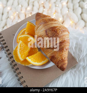 Breakfast of Croissant, Orange Fruit on the Note Book. Decoration Set Up Stock Photo