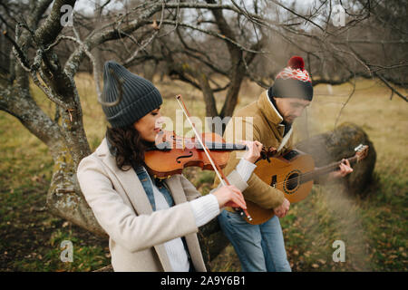 Two musicians playing in duet inside a beautiful leafless autumn forrest Stock Photo