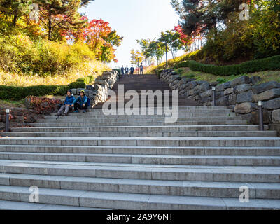 SEOUL, SOUTH KOREA, NOVEMBER 4, 2019: couple of elderly tourists rest on the steps of the stairs and a group of guys descend from above in colorful ci