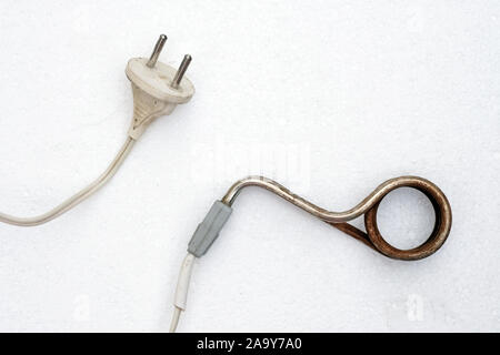 Old rusted immersion heater on a white background. Electrical appliance for heating water. Household boiler. Stock Photo