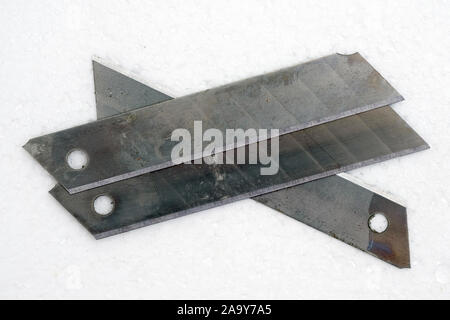 Blades for stationery knives, close-up. Segmented knife blades on a white background. Stationery. Stock Photo