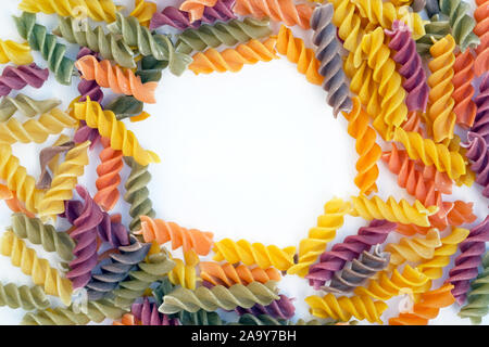 Colored pasta in the shape of a spiral. Pasta of different colors top view. mockup flour products. macaroni on a white background. Stock Photo