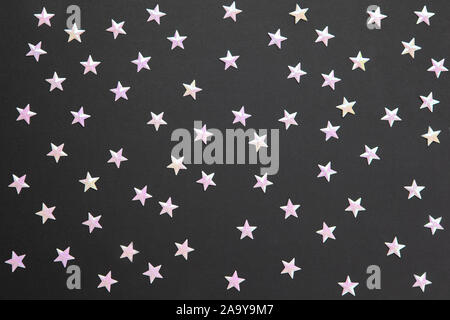 Chaotic pattern from numerous pearl confetti in form of small stars on black paper background. Celebration, holidays, sales, fashion concept. Horizont Stock Photo