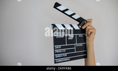 Close up female holding in hand classic director clear empty black film making clapperboard isolated on light gray background. Stock Photo