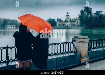 Madrid, Spain - Nov 9, 2019: Two women admire the lake and monument to King Alfonso XII on a rainy winter day, Madrid, Spain Stock Photo