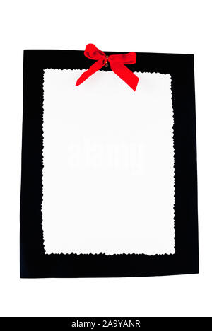 white blank paper with a scalloped edge on top of a piece of black cardboard with a red ribbon. Isolated White Background. Stock Photo
