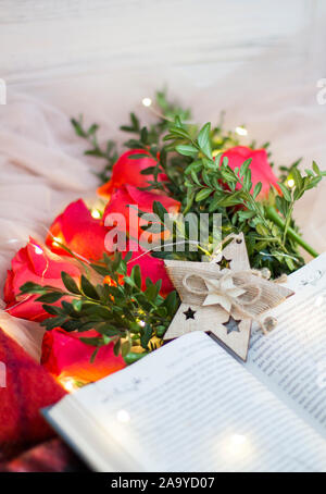 Composition: red roses with boxwood, a book, a garlands and a red blanket. Stock Photo
