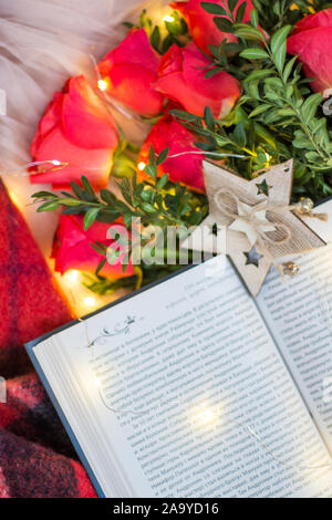 Composition: red roses with boxwood, a book, a garlands, red blanket and star. Stock Photo