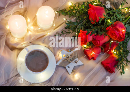 Composition: red roses with boxwood, garlands, candles, star and cup coffee (tea) Stock Photo