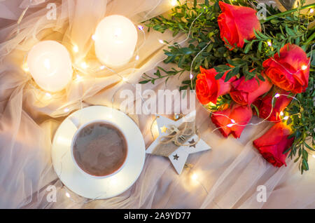 Composition: red roses with boxwood, garlands, candles, star and cup coffee (tea) Stock Photo