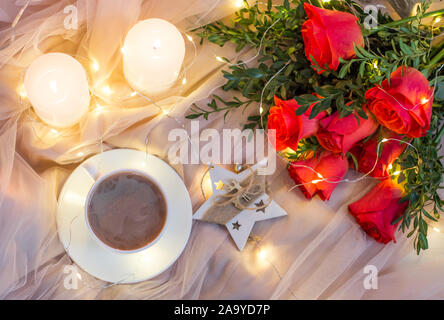 Composition: red roses with boxwood, garlands, candles, star and cup coffee (tea) Stock Photo
