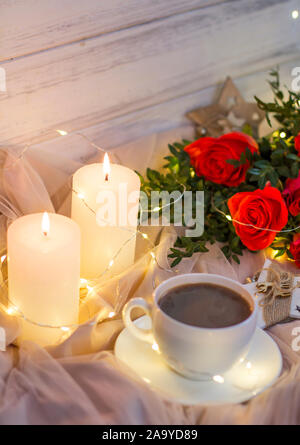 Composition: red roses with boxwood, garlands, candles, star and cup coffee (tea) Stock Photo