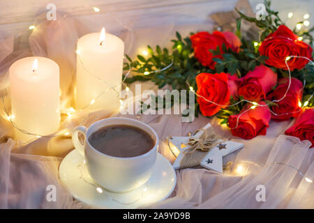 Composition: red roses with boxwood, garlands, candles, star and cup coffee (tea) Stock Photo