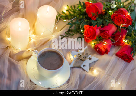 Composition: red roses with boxwood, garlands, candles, star and cup coffee (tea) Stock Photo
