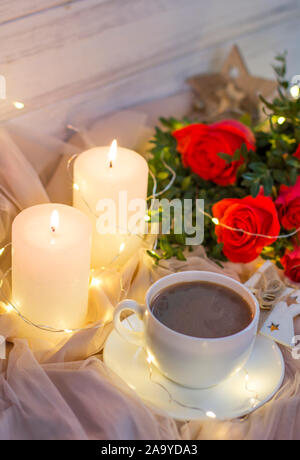 Composition: red roses with boxwood, garlands, candles, star and cup coffee (tea) Stock Photo