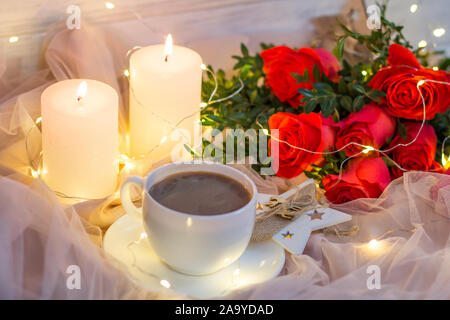 Composition: red roses with boxwood, garlands, candles, star and cup coffee (tea) Stock Photo