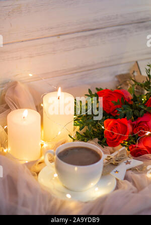 Composition: red roses with boxwood, garlands, candles, star and cup coffee (tea) Stock Photo