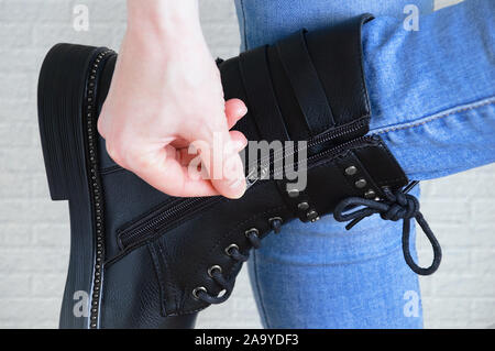 Closeup caucasian girl hand unzips on black boots. Stock Photo
