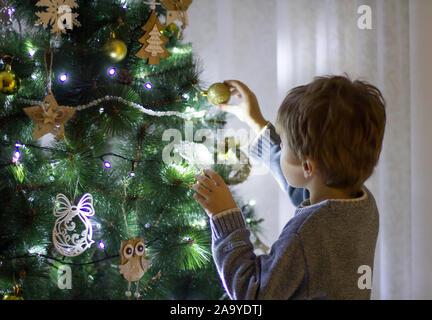 The boy decorates the Christmas tree Stock Photo