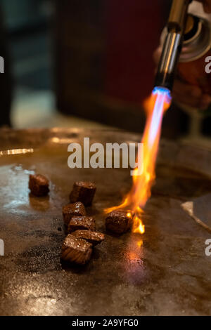 Cooking of beef teppanyaki recipe japanese grilled beef on cooking pan with scraper and gas burner flame Stock Photo