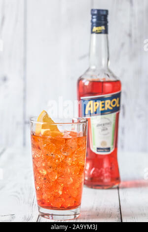SUMY, UKRAINE - AUGUST 29, 2018: Glass of Aperol Spritz cocktail with bottle of Aperol on the white wooden background. Aperol is famous Italian aperit Stock Photo
