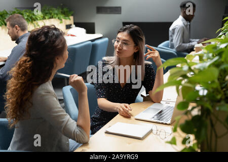 Young vietnamese manager in eyeglasses discussing project details with colleague. Stock Photo