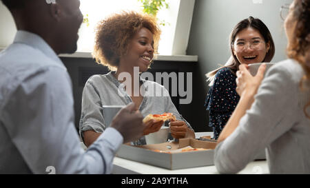 Mixed race colleagues enjoying sharing lunch at workplace. Stock Photo