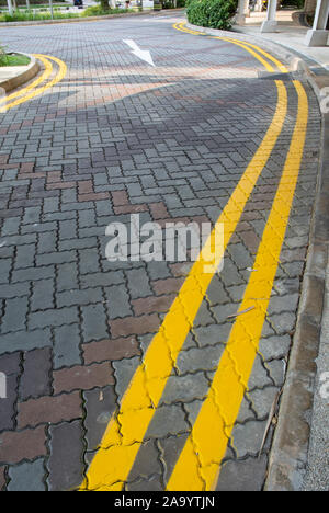double yellow lines painted on interlocking concrete pavement Stock Photo