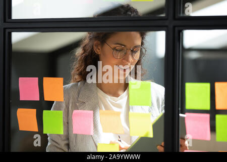Smiling smart businesswoman using kanban agile scrum method glass board. Stock Photo