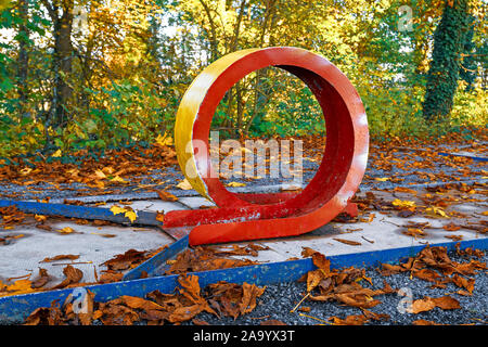 Old untended miniature golf course with loop and very chipped red paint covered in yellow autumn leaves Stock Photo