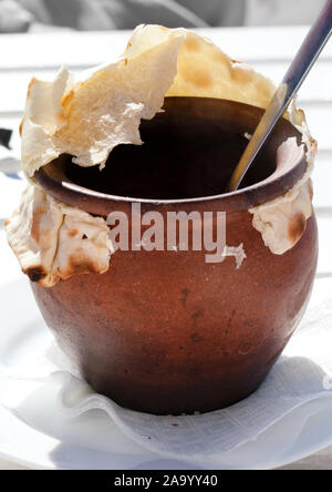 Clay pot covered with bread at outdoor cafe in sunny day Stock Photo