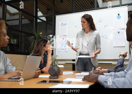 Concentrated mixed race millennial employees listening to speaker. Stock Photo