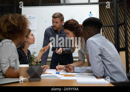 Busy millennial group of motivated mixed race teammates discussing project. Stock Photo