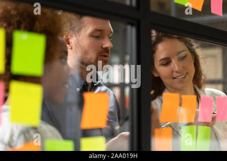 Close up headshot smiling diverse colleagues working near kanban board. Stock Photo