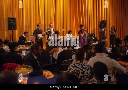 Audience members, from the back, watch performers on stage during a Black History Month cabaret presented by the Dunbar-Baldwin-Hughes Theatre Company (DBH), at the Johns Hopkins University, Baltimore, Maryland, February 20, 2009. From the Homewood Photography Collection. () Stock Photo