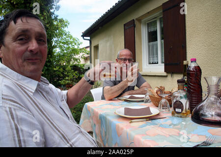 2 men saying Cheers at a dinner table outside, France Stock Photo
