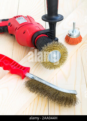 Drill and abrasive brushes with metal and nylon wire on a wooden surface. Tools for cleaning, polishing and grinding of wood and metal. Front view. Stock Photo