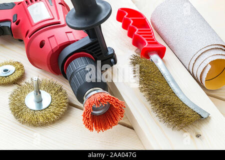 Drill, sandpaper and abrasive brushes with nylon and metal wire on a wooden surface. Tools for cleaning, polishing and grinding of wood and metal. Stock Photo