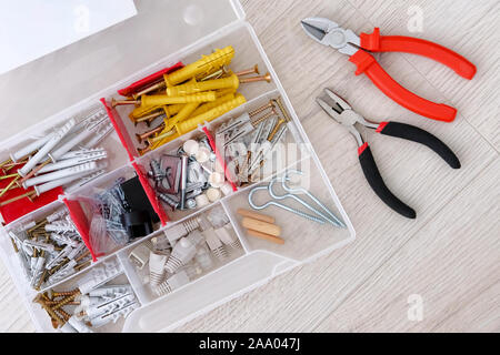 Repair in house with special tools. Red special tools, parts and pliers on white wooden background, closeup. Stock Photo